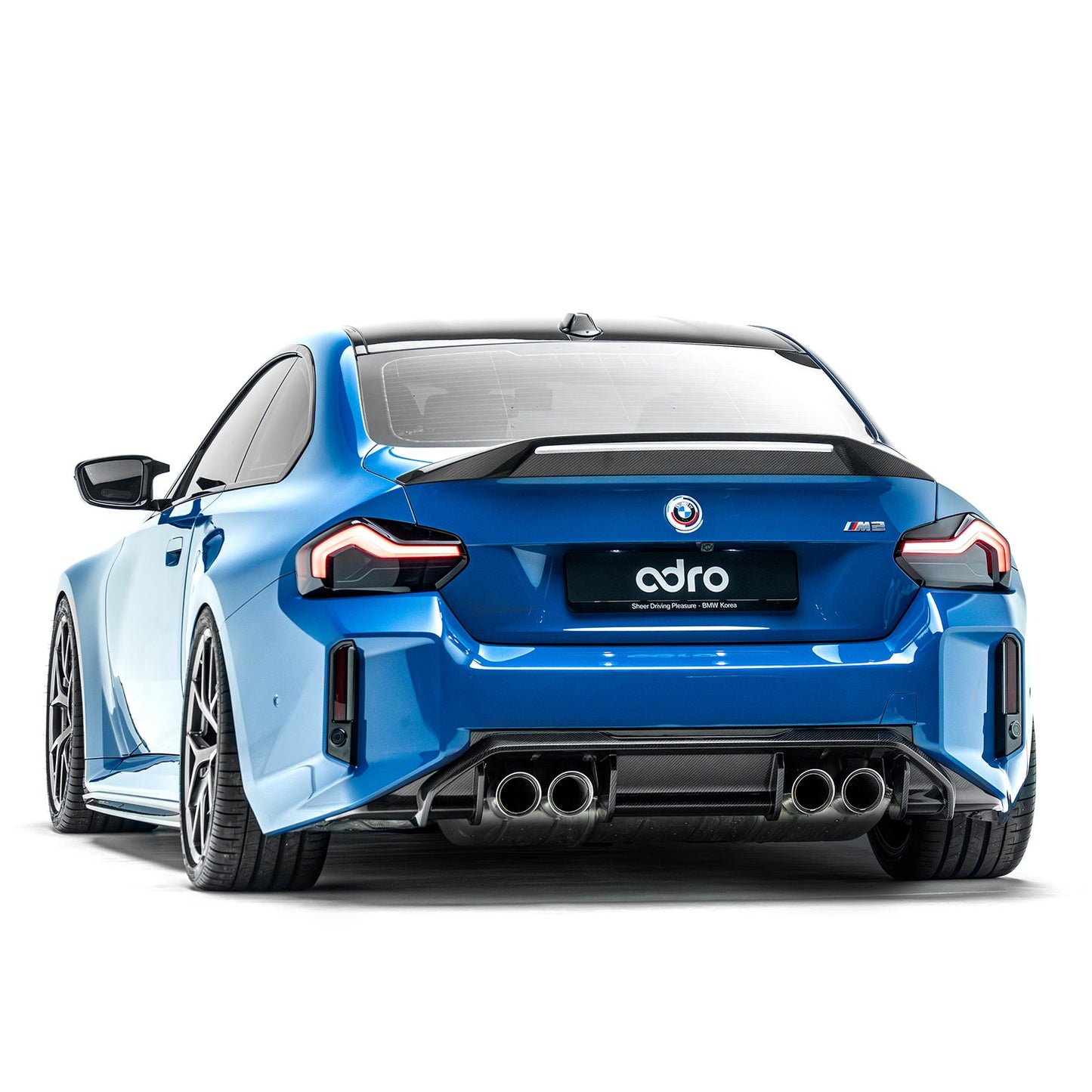 Blue coupe rear spoiler with black carbon-style lip over rear deck