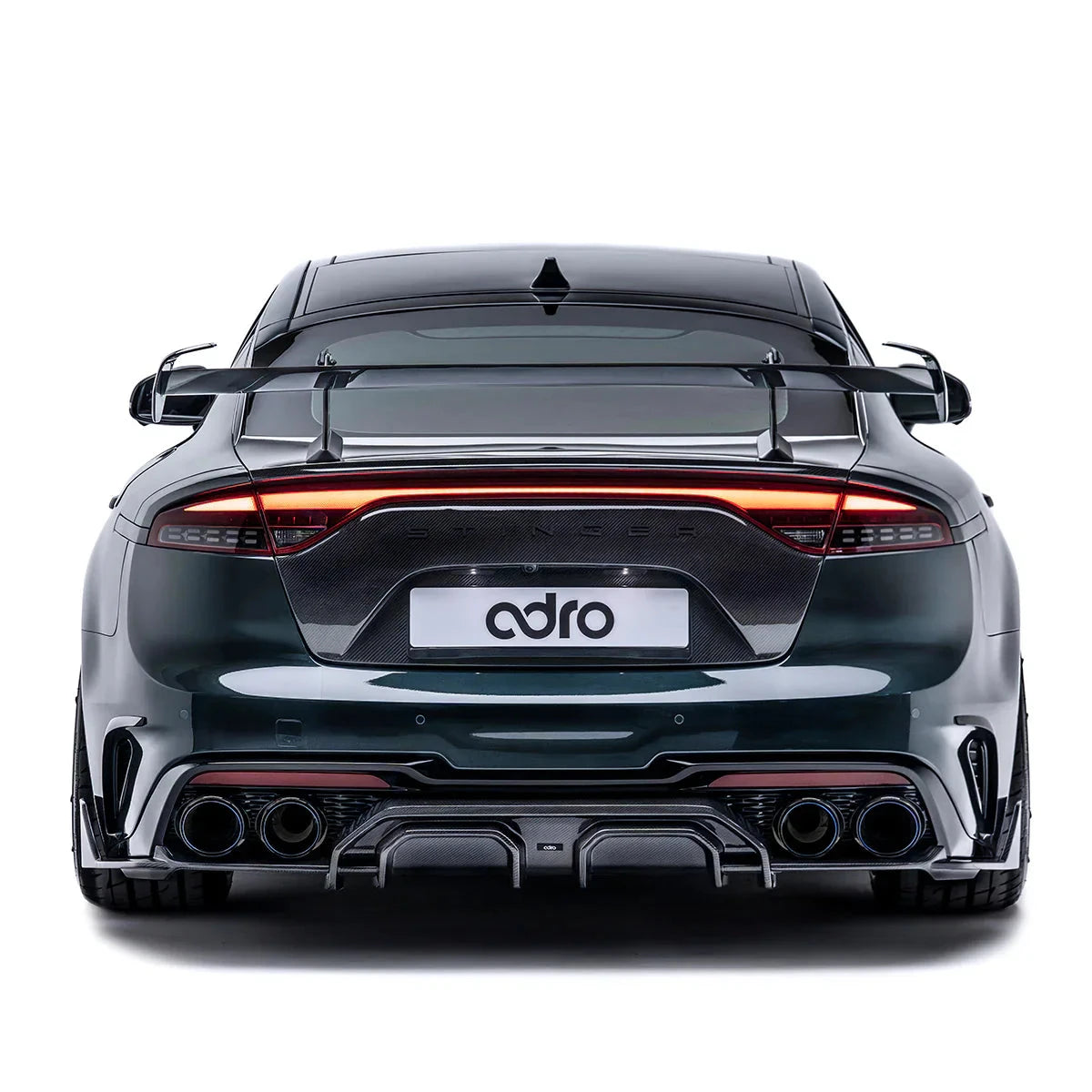 ADRO carbon fiber rear diffuser for KIA Stinger installed, rear view, dark green car on white background.