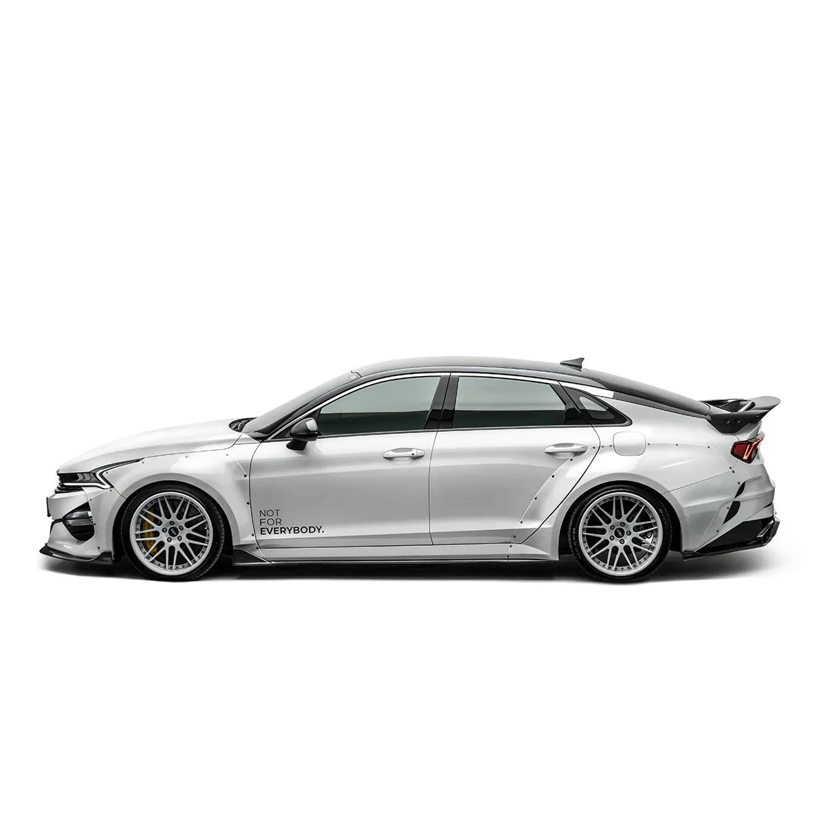 Carbon fiber style trunk spoiler visible on the rear of the white sedan