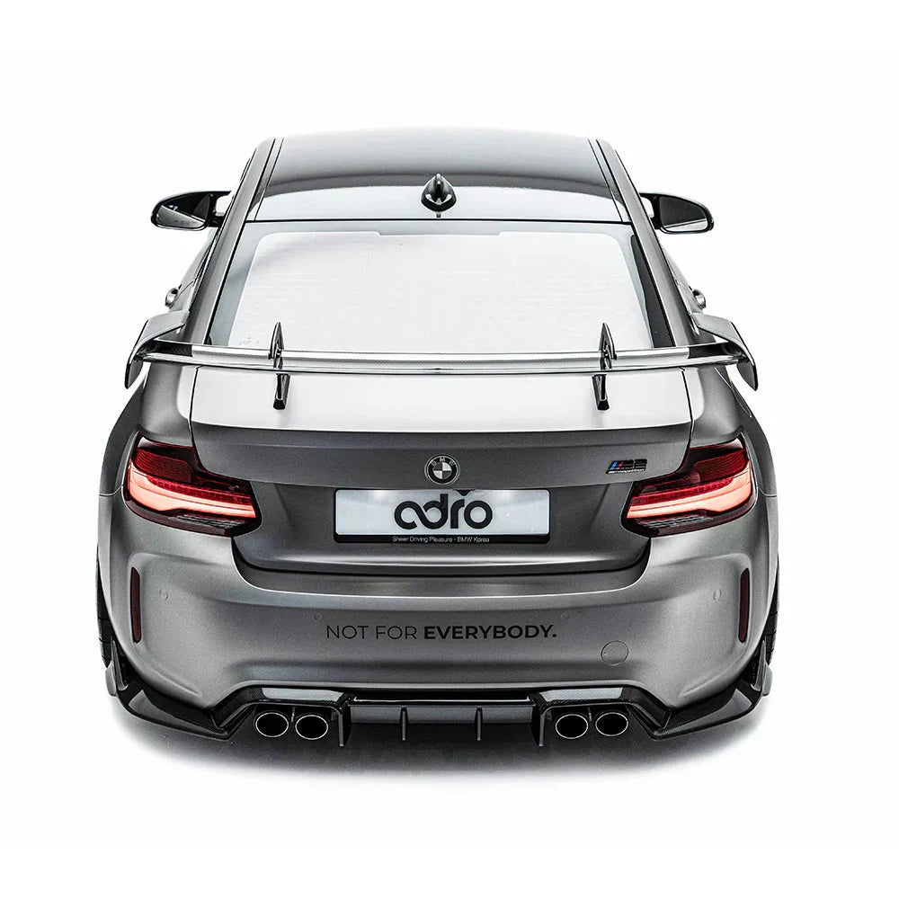 ADRO Swan Neck Wing on BMW F87 M2, rear view showing quad exhausts, matte gray, on white background.