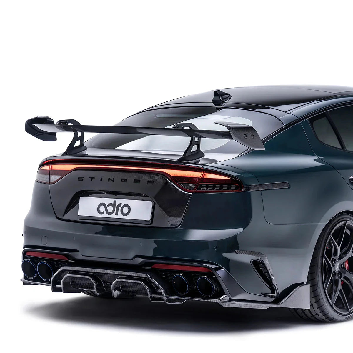 KIA sports sedan close-up rear view, dark teal with rear spoiler and quad exhaust