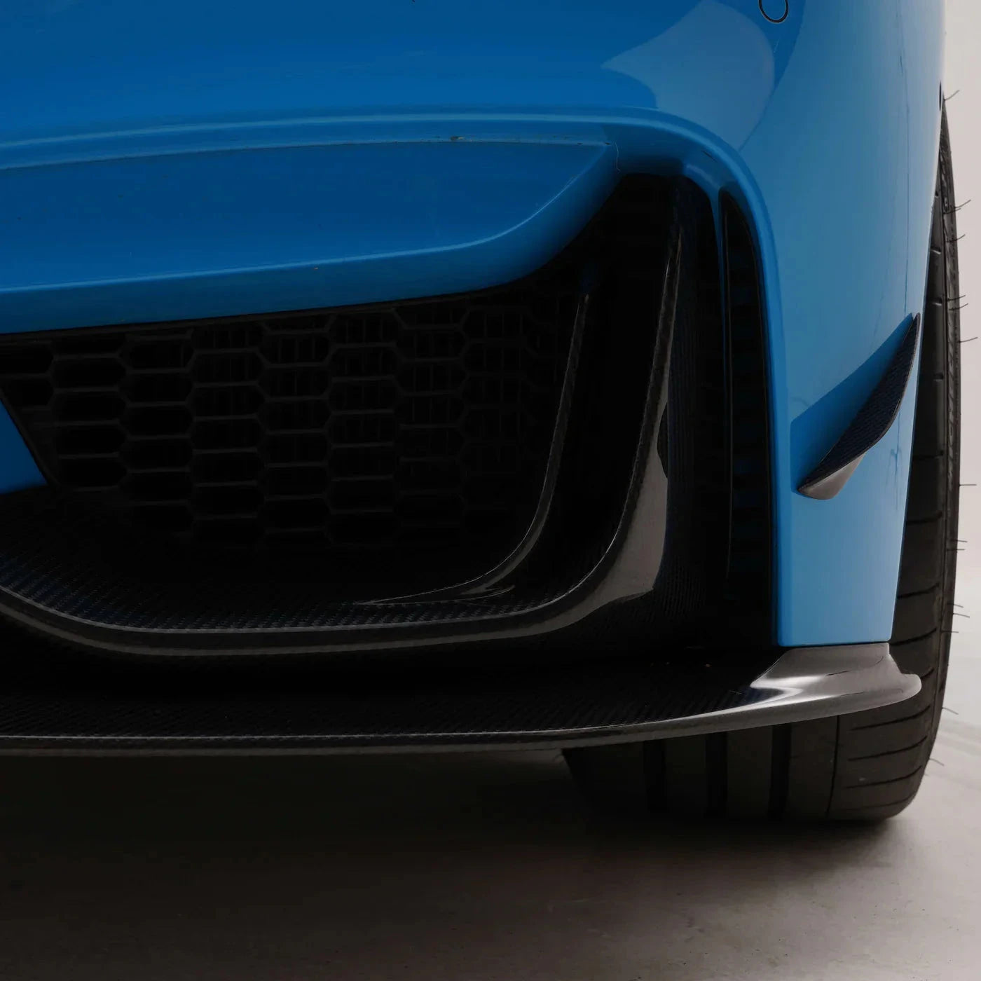 ADRO carbon fiber air ducts for BMW F8X M3/M4, detail view of front right bumper and tire.
