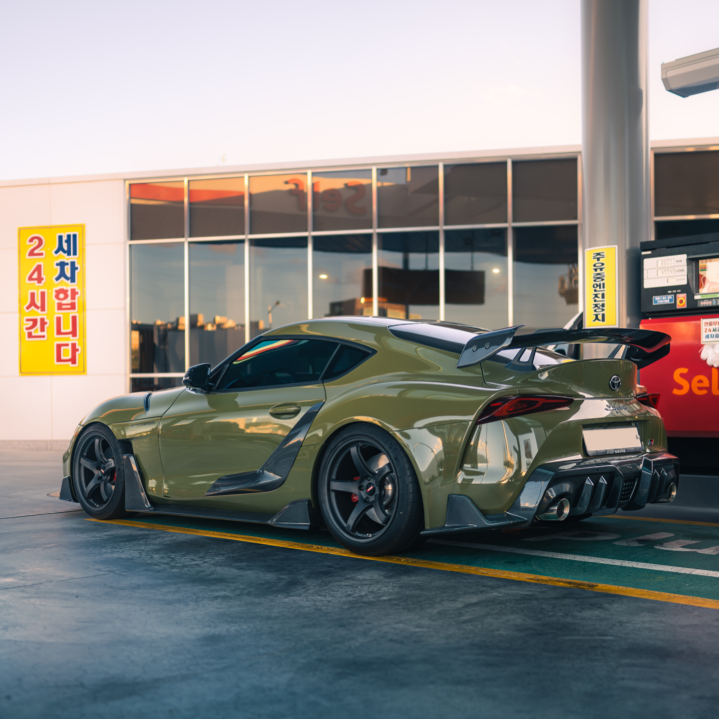 Green Toyota GR Supra sports car, rear three-quarter view with large rear spoiler