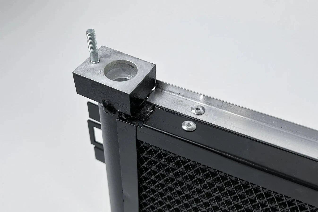 Engine oil cooler with top mounting boss and black housing beside mesh core