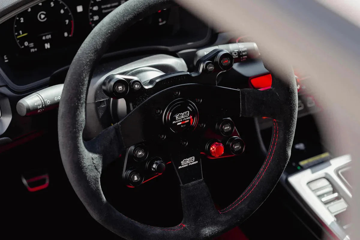 Steering wheel horn cap adapter installed on black wheel, near front controls