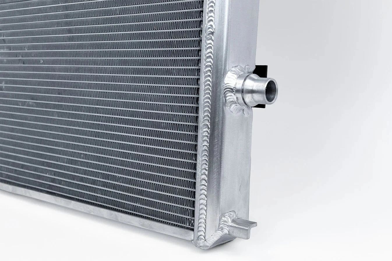 Cooling module heat exchanger corner with silver inlet fitting and mounting tab