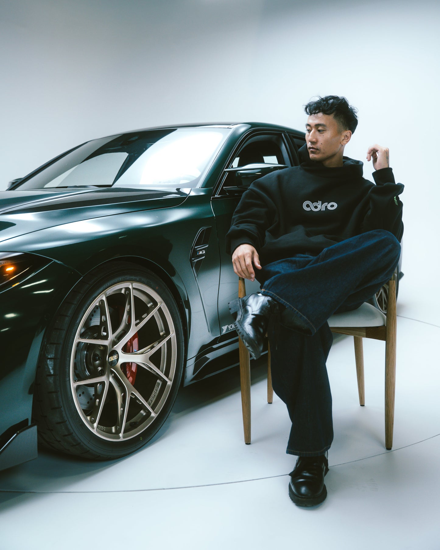 Black hoodie with chest ADRO logo worn by seated person