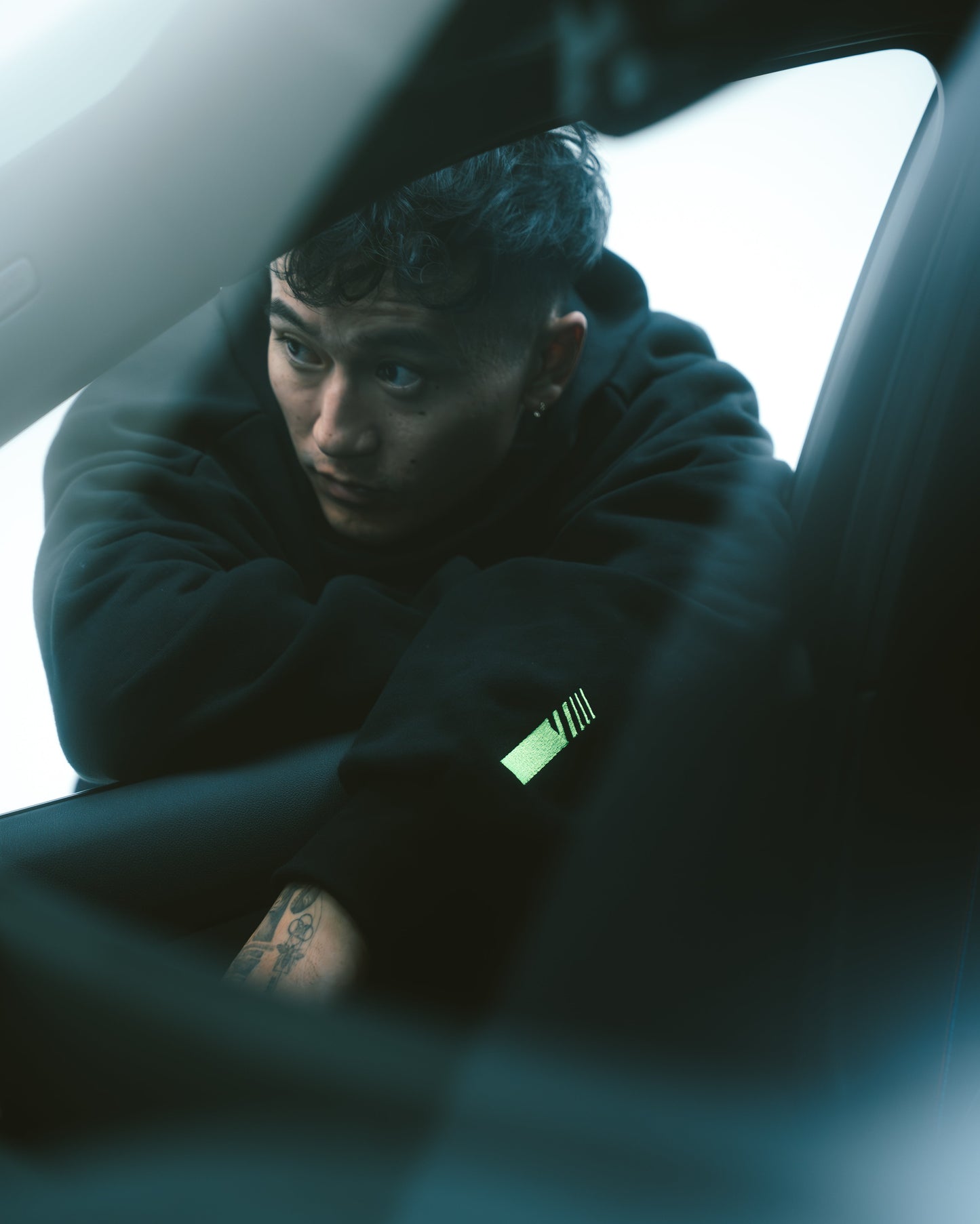 Black hoodie worn by person with neon green sleeve graphic