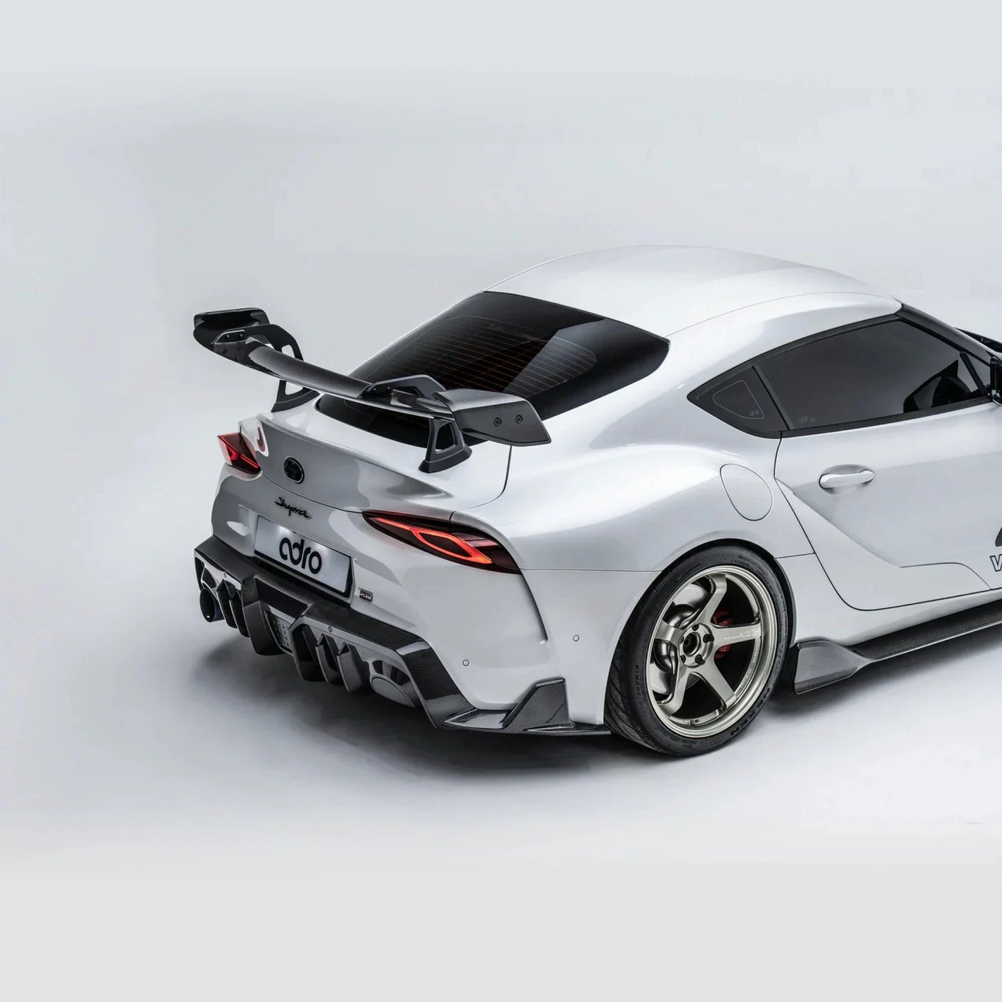 ADRO carbon fiber rear diffuser for Toyota GR Supra, installed view from rear three-quarter angle on plain background.