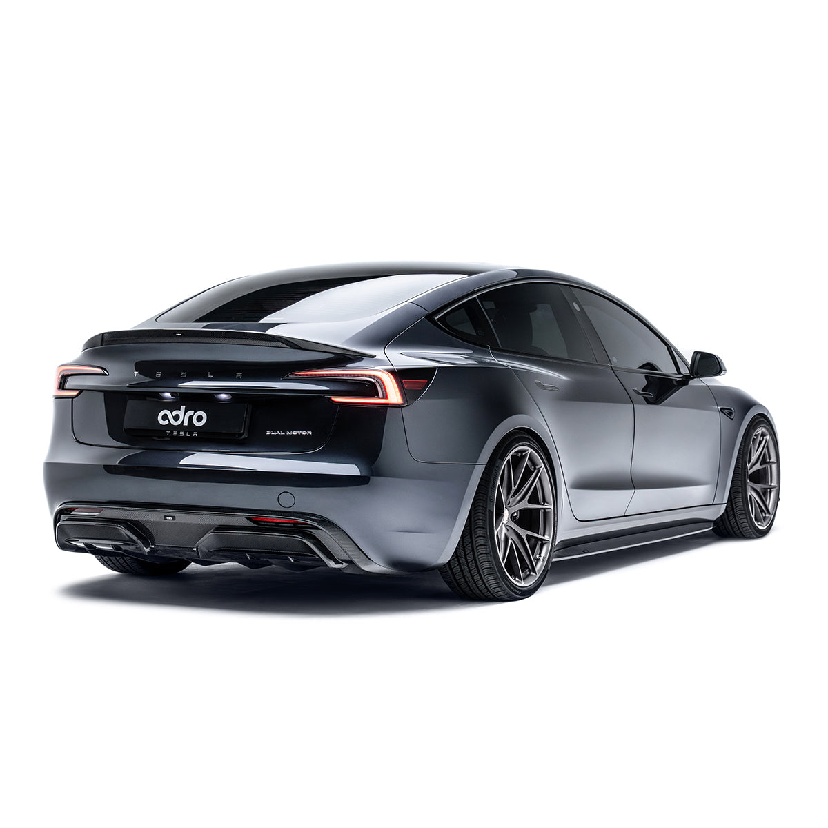 Carbon fiber rear trunk spoiler with black mesh finish on gray Tesla Model 3 Highland