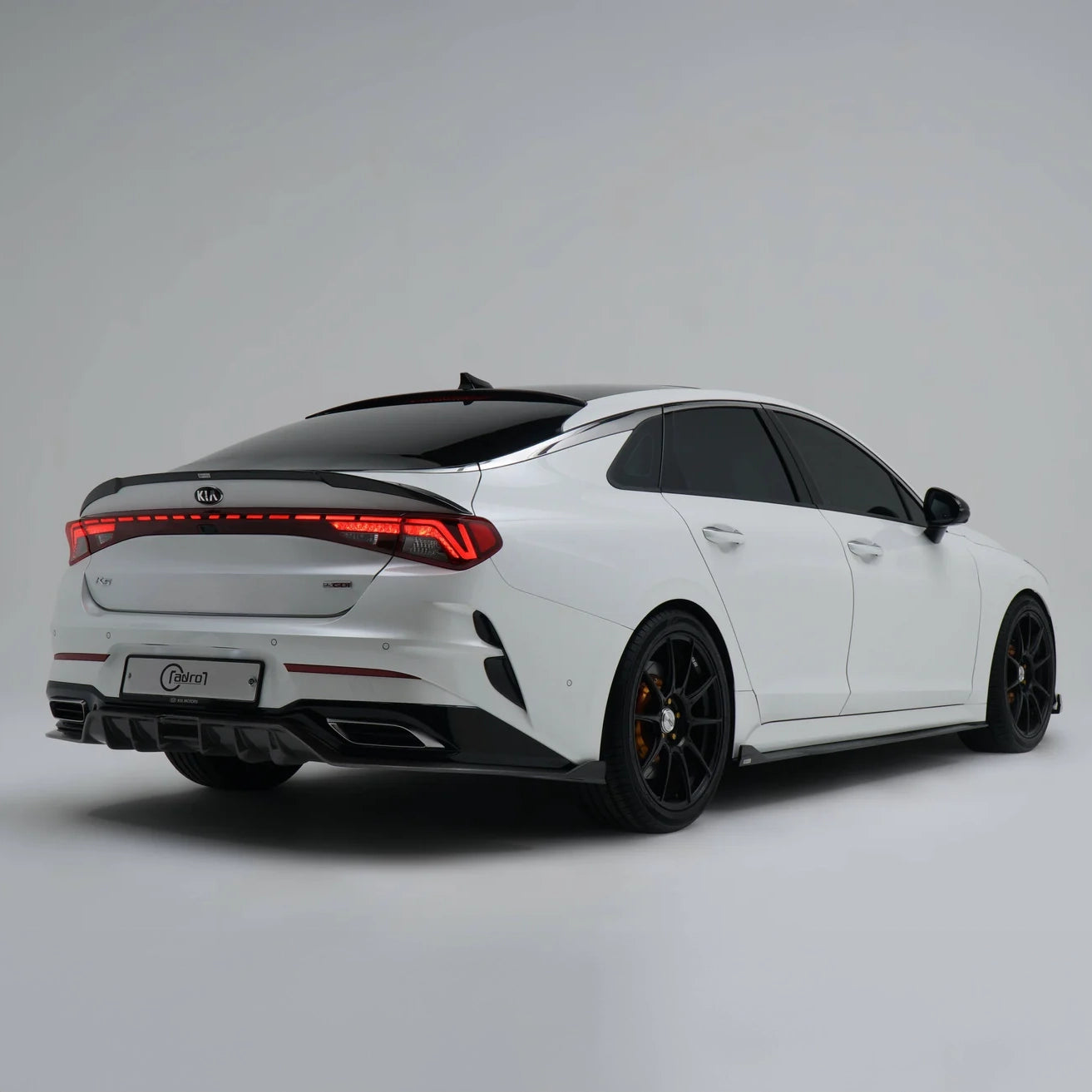 White sport sedan rear three-quarter view with red taillights and black wheels