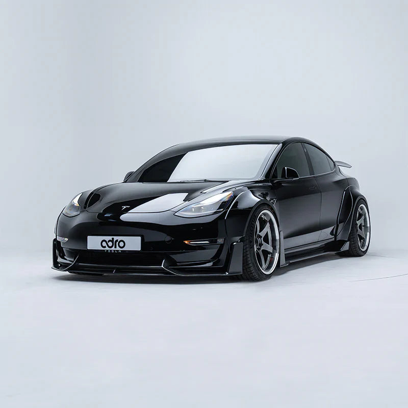 ADRO widebody kit on Tesla Model 3, front three-quarter view, installed and shown in a light gray studio.