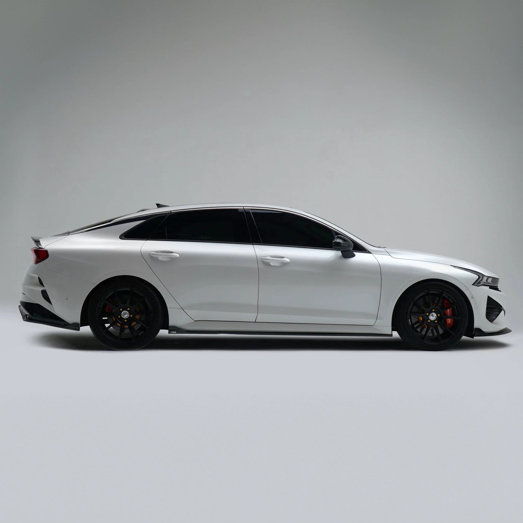 White sport sedan side profile with black wheels and low stance