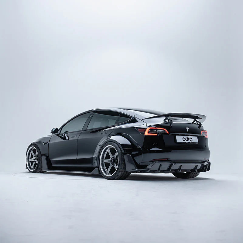 ADRO carbon fiber widebody kit and rear spoiler on Tesla Model 3, three-quarter view in white studio.