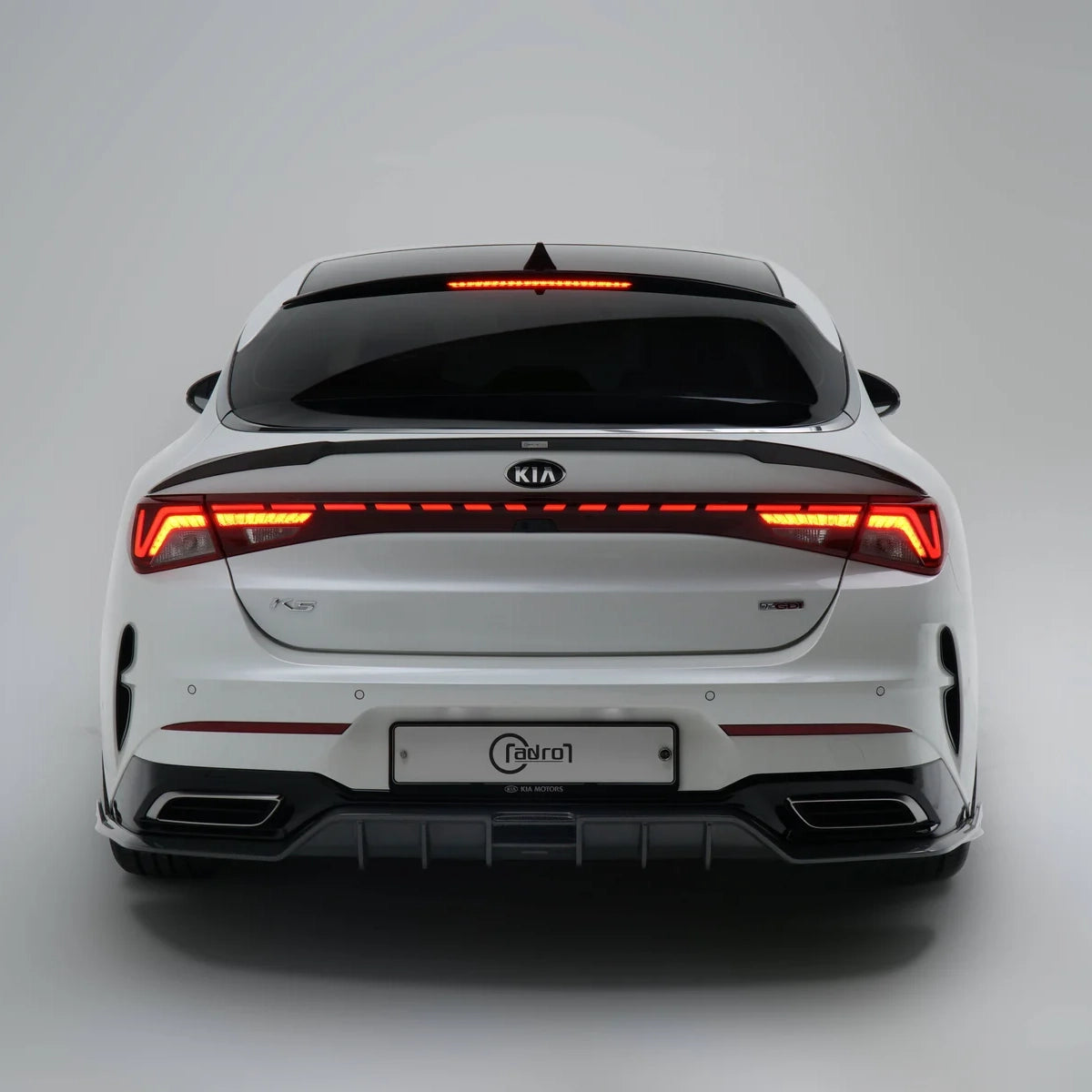 White sport sedan rear view with red light bar and black diffuser