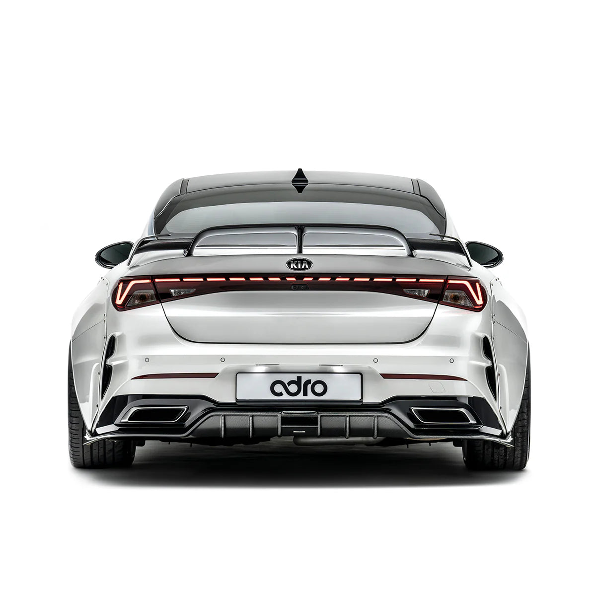 White sport sedan rear view with red taillight bar, black spoiler, and diffuser