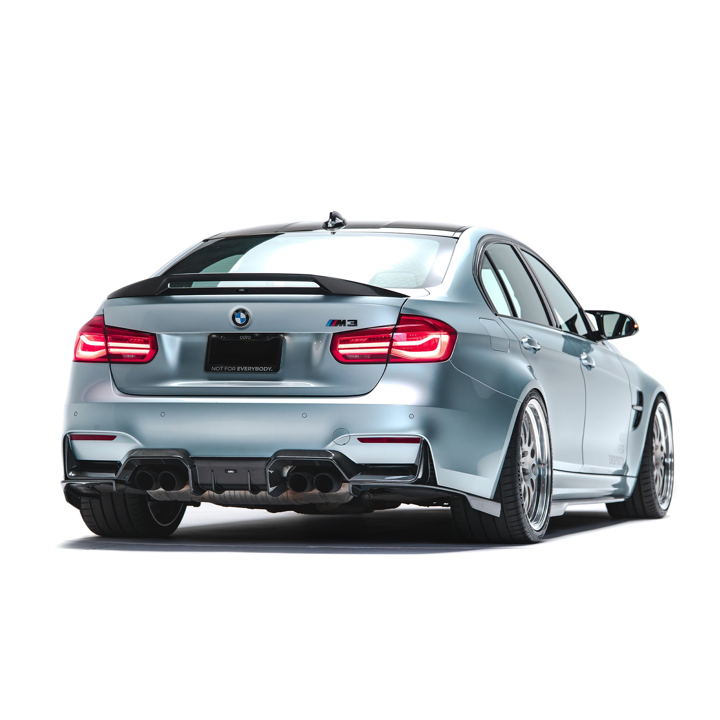 Carbon fiber side skirts, dark rear-side trim on light blue sedan.
