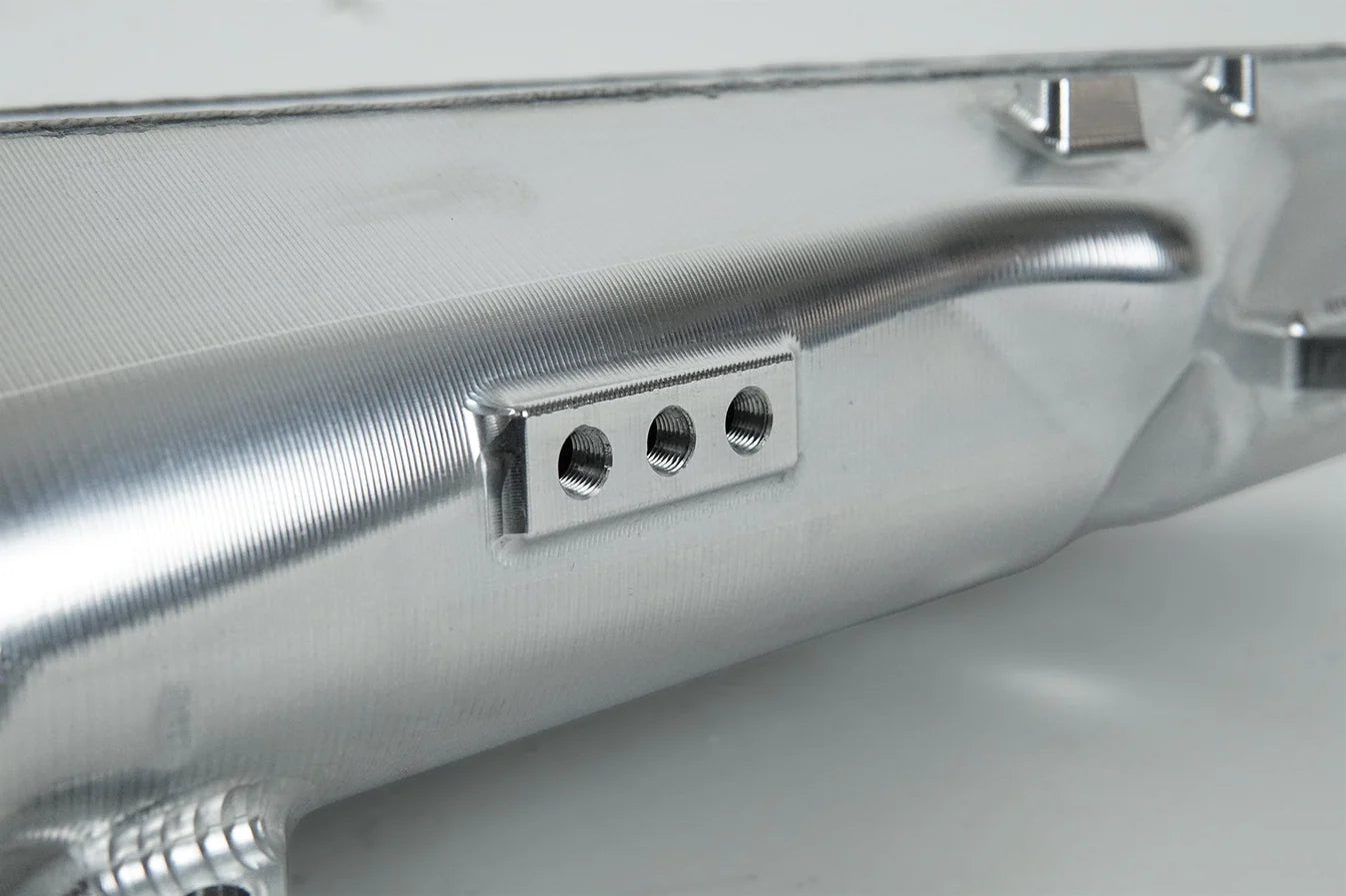 Charge-air cooler manifold, silver side close-up with threaded fittings on mounting plate