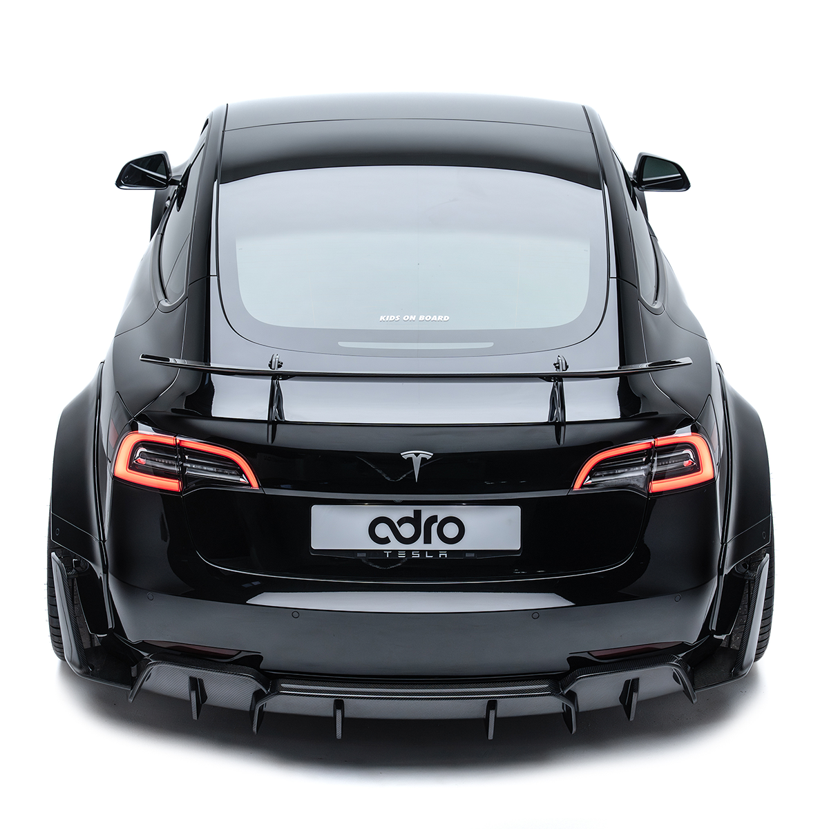 ADRO carbon fiber aero kit and spoiler on Tesla Model 3 Widebody, rear view, shown on white background.